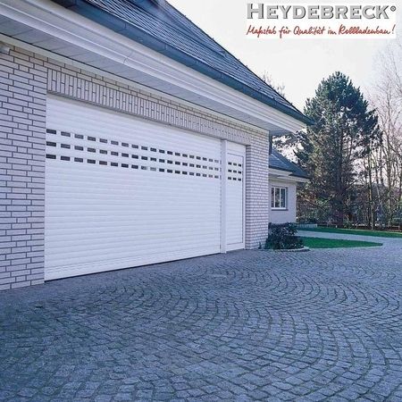 Garage mit zwei großen weißen Rolltoren in einem hellen Ziegelbau