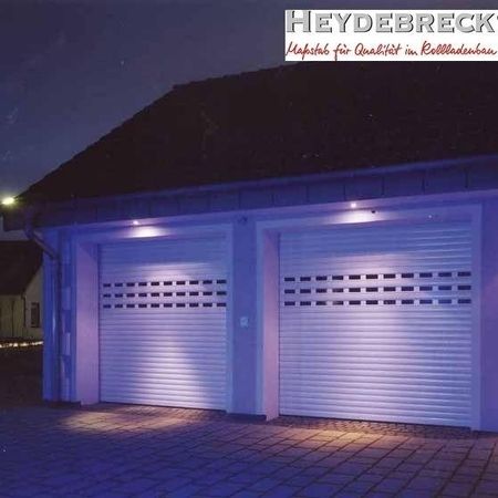 Garage mit zwei beleuchteten weißen Rolltoren bei Nacht